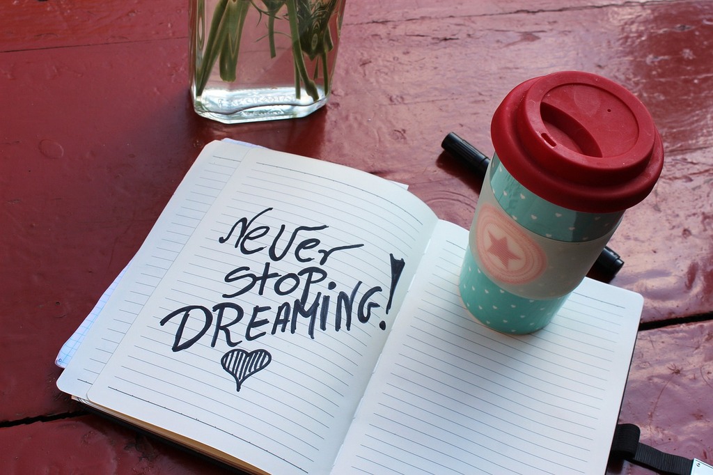 Never Stop Dreaming!と書かれたノートと飲み物の画像